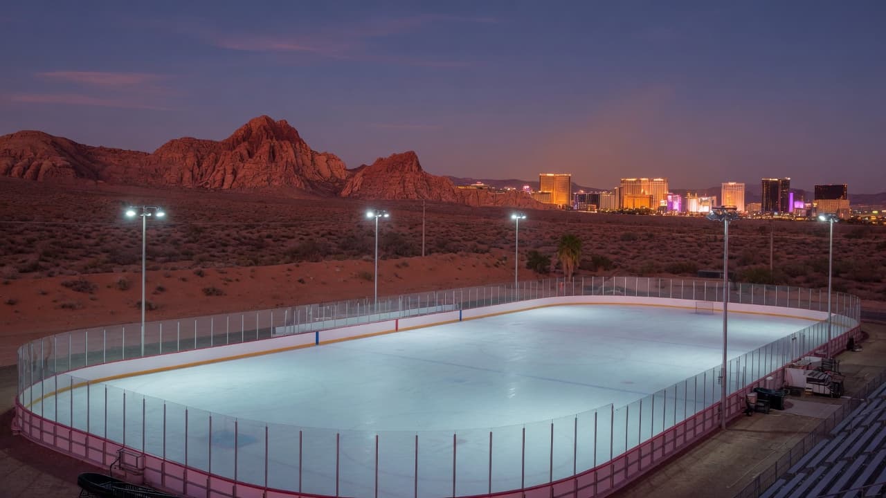 Empty ice sheet at dusk with desert mountains and a distant Strip skyline.